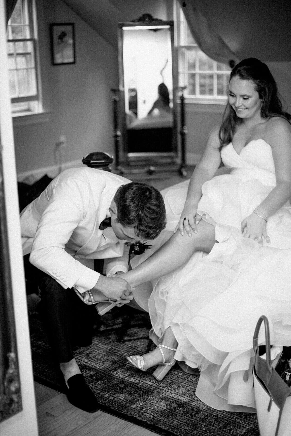 25-kara-loryn-photography-groom-helps-bride-change-heels