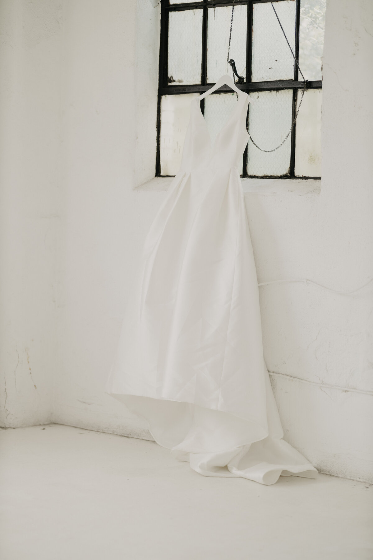 a wedding gown hanging from a window