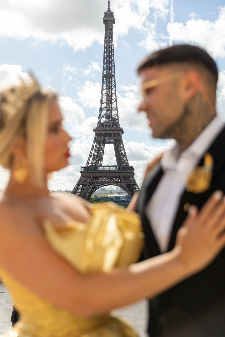 Artistic Paris couple photo composition, blurred foreground embrace, centered Eiffel Tower backdrop