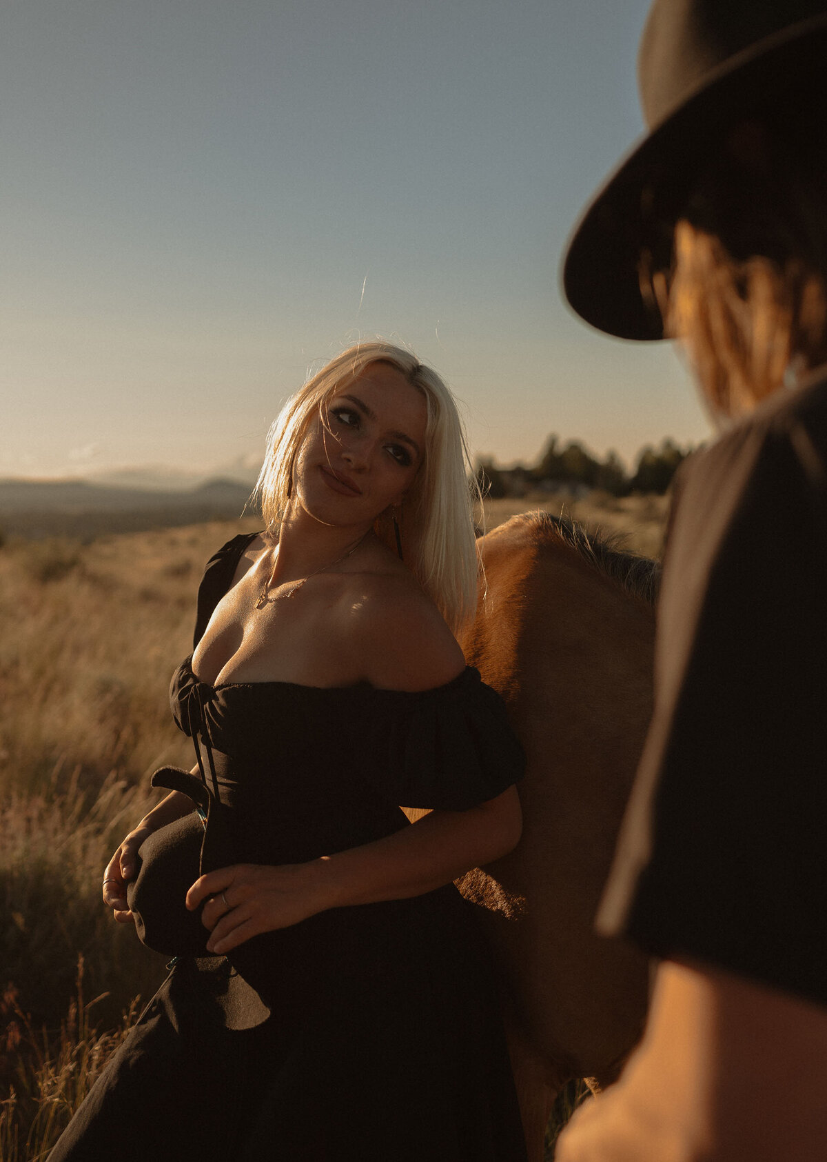 engaged couple in love, gazing into each other's eyes with their horse standing close by during sunset
