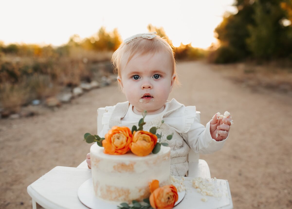 baby girl eating a beautiful cake outdoors for her photos