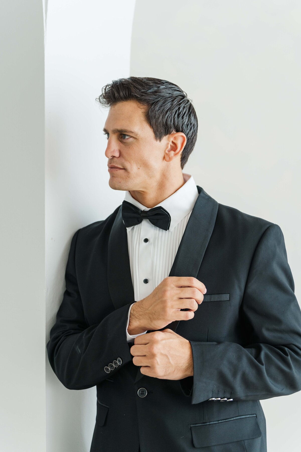 groom looking away from  the camera while fixing his sleeve