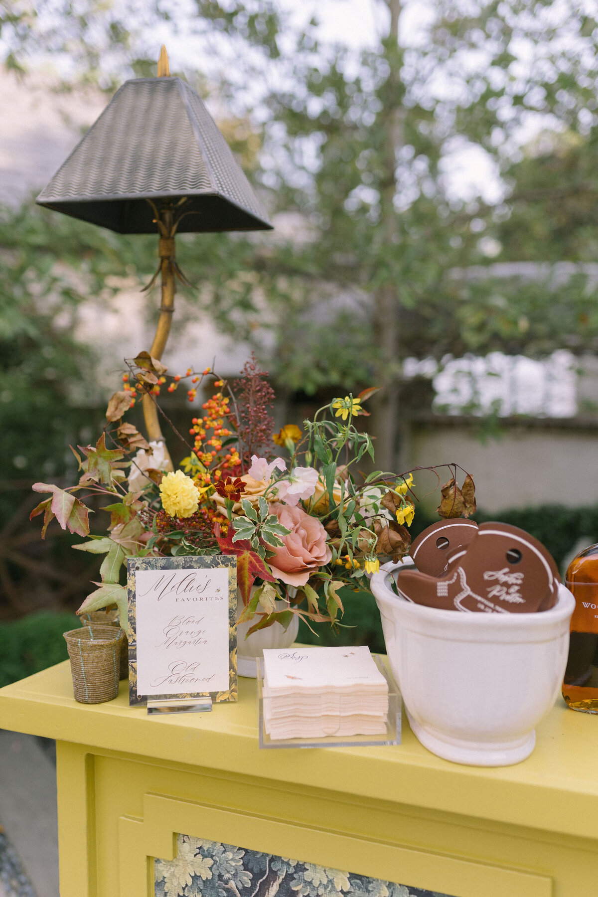 Accent floral for outdoor wedding reception. Clear tented wedding reception in the family's back yard creating an intimate wedding reception environment. Whimsical and organic floral design in colors of copper, yellow, blush,and brown. Fall florals with sweet peas, dahlias, butterfly ranunculus, roses, mums, and bittersweet berries. Design by Rosemary & Finch Floral Design in Nashville, TN.