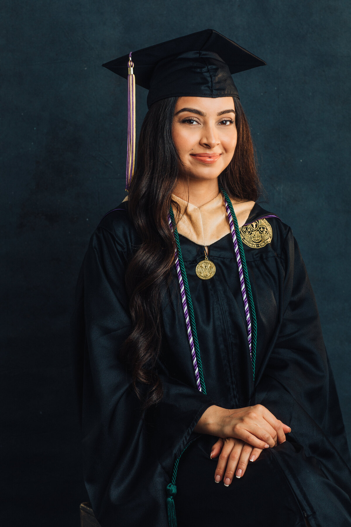 Graduation Portrait Of Young Woman Sitting On a Stool Holding Her Hands Los Angeles