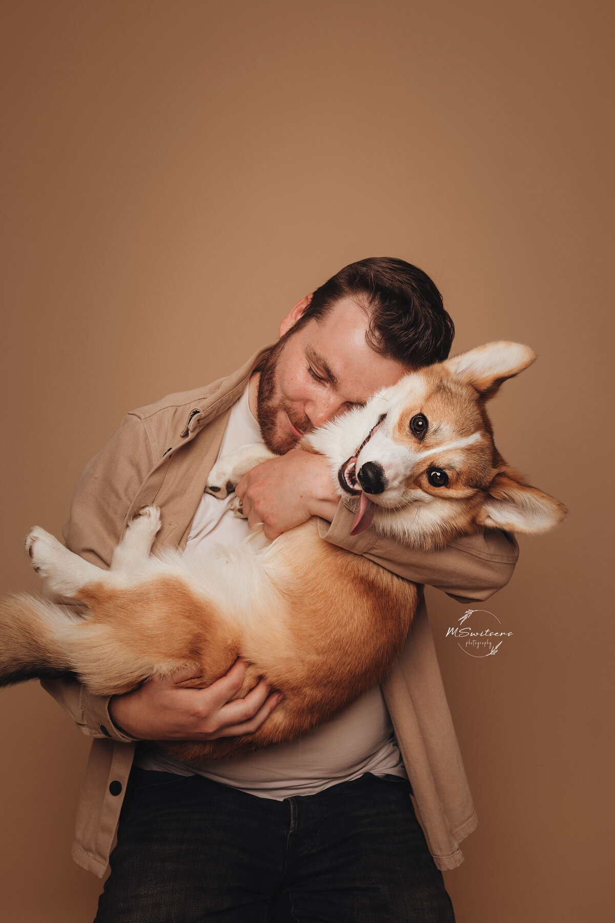 Een corgi en zijn dogdad al knuffelend tijdens een hondenfotoshoot in de studio te Geel