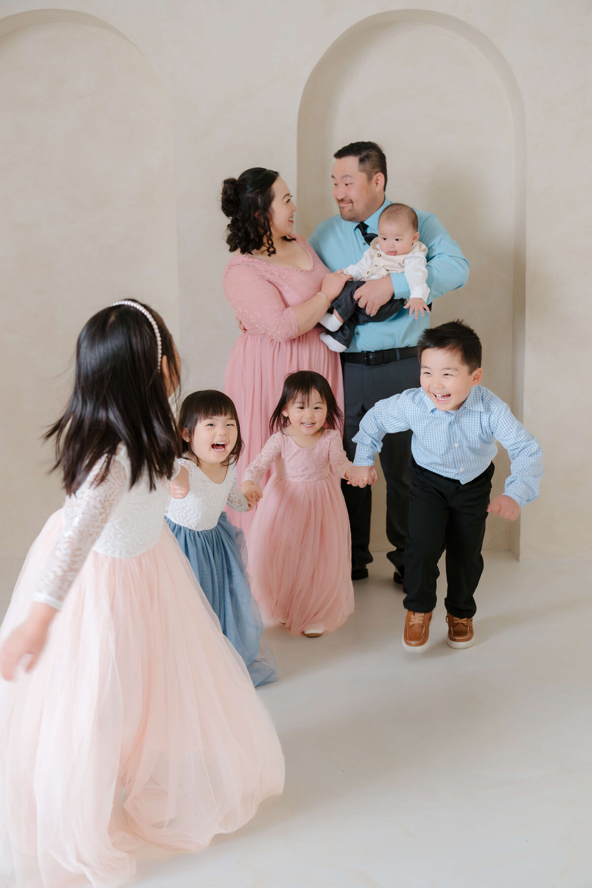 Children joyfully running toward their parents during a vibrant family studio shoot in soft natural light.