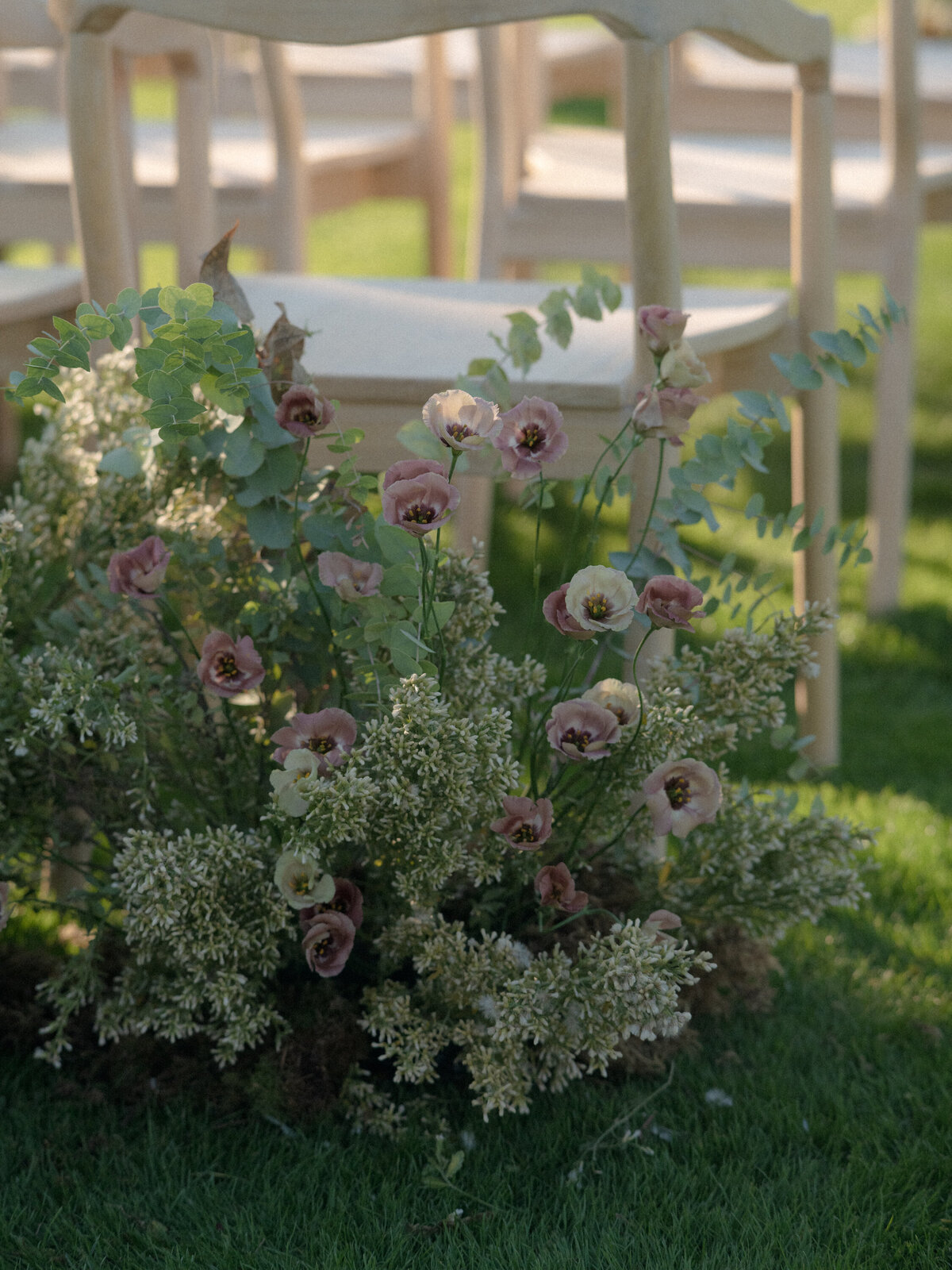 Light wood ceremony chair adorned by  light colored flowers