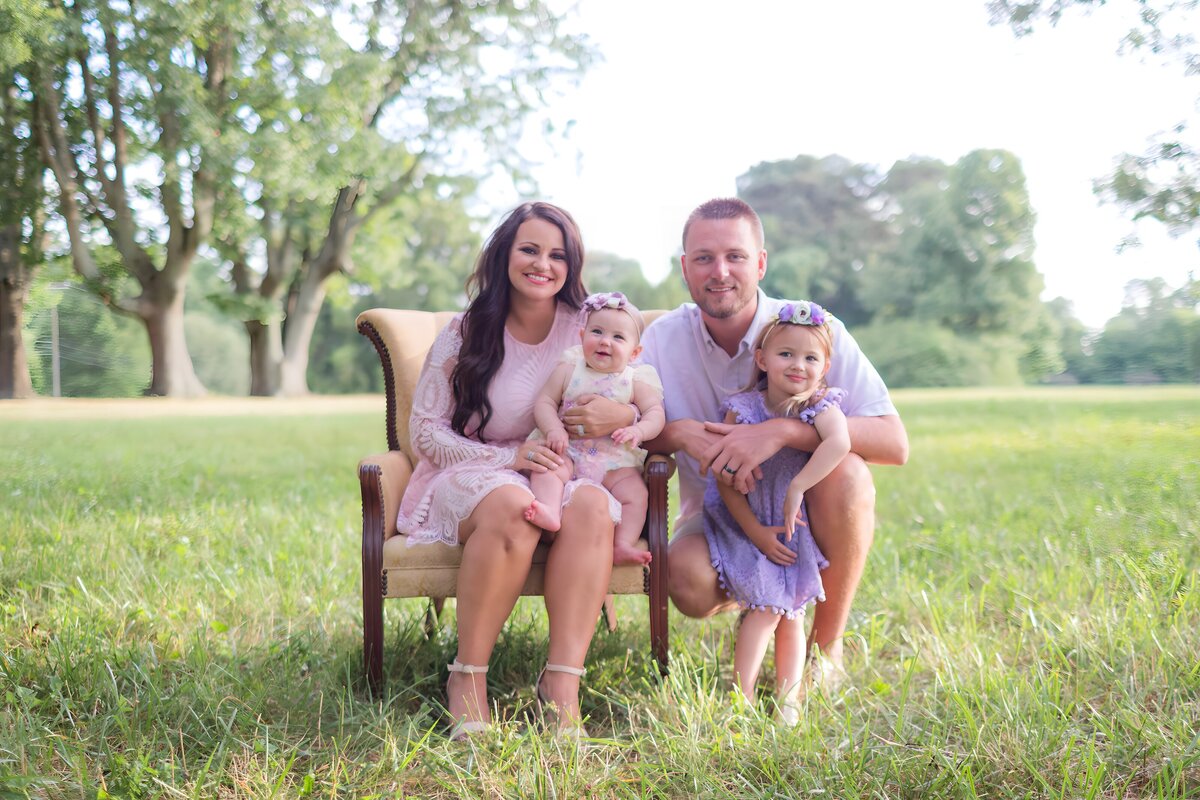 Family of four cuddled up together on chair during family photo session in Mooresville NC