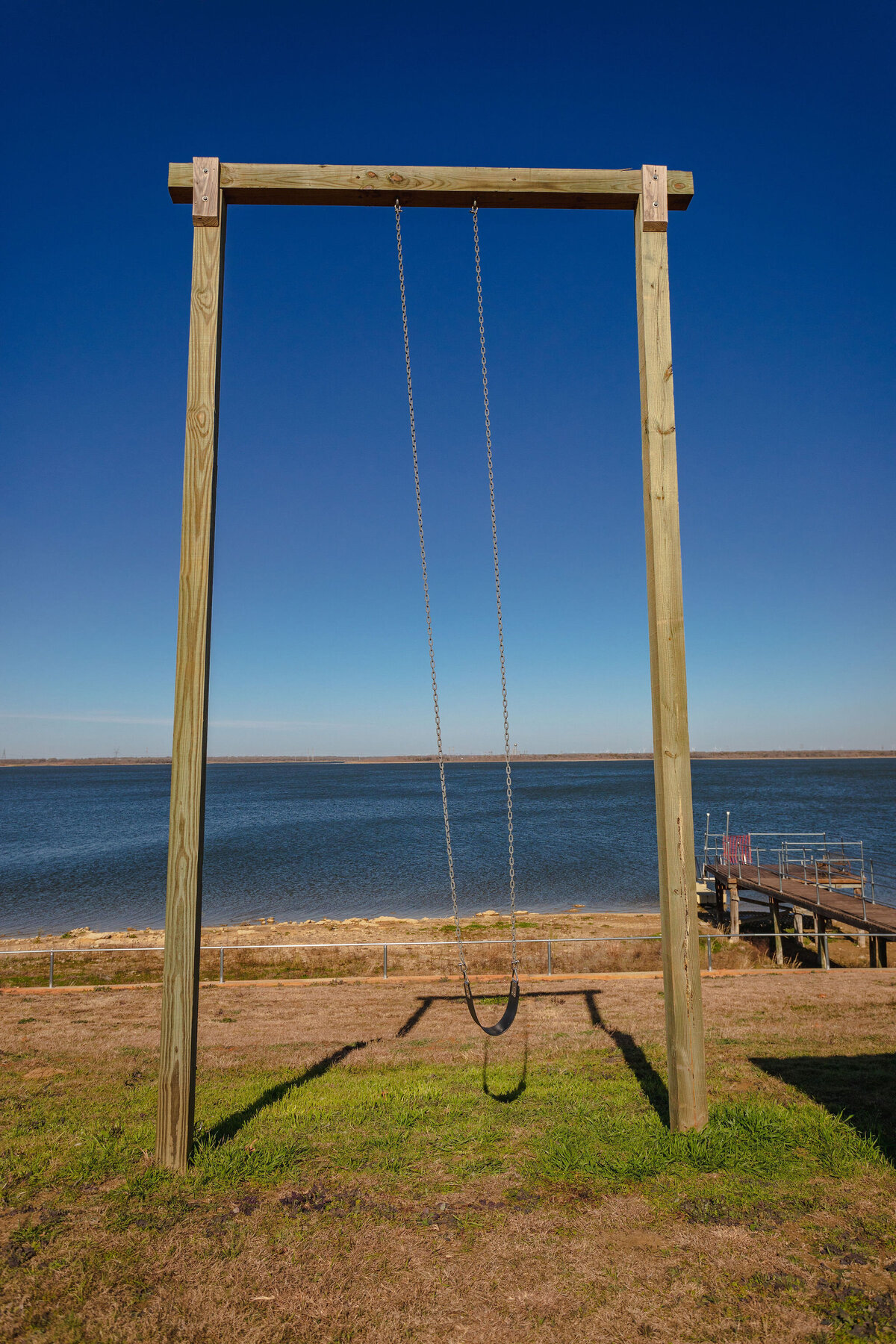 Outdoor swing area overlooking Tradinghouse Lake at this 2-bedroom, 2-bathroom lakeside vacation rental home for 6 guests on Tradinghouse Lake with privacy access to a fishing dock and boat launch pad, ping pong table, gazebo, free wifi and free parking in Waco, TX.
