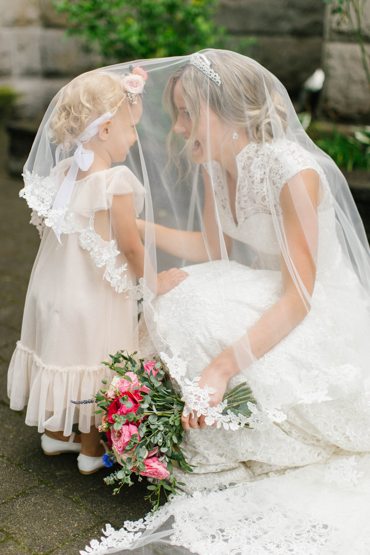 Bride and her flower girl together under her veil