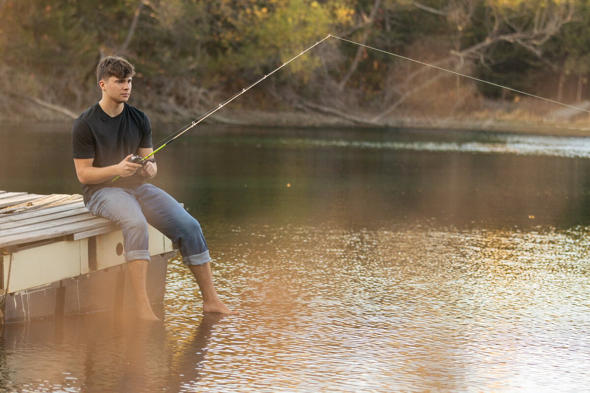 A senior guy sitting on a dock on a lake fishing in Lawrence, KS