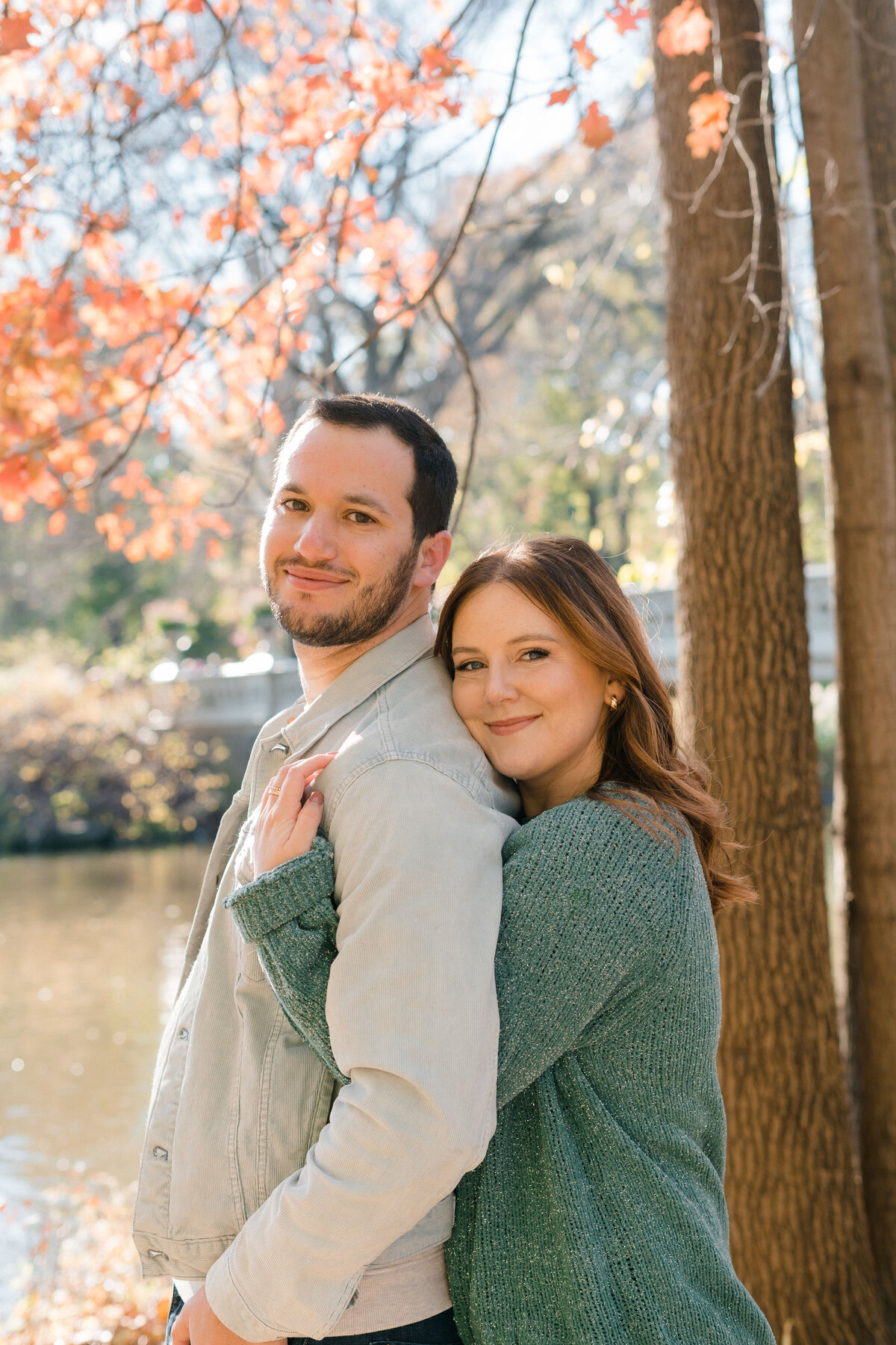 woman wrapping arms around man from behind while they smile