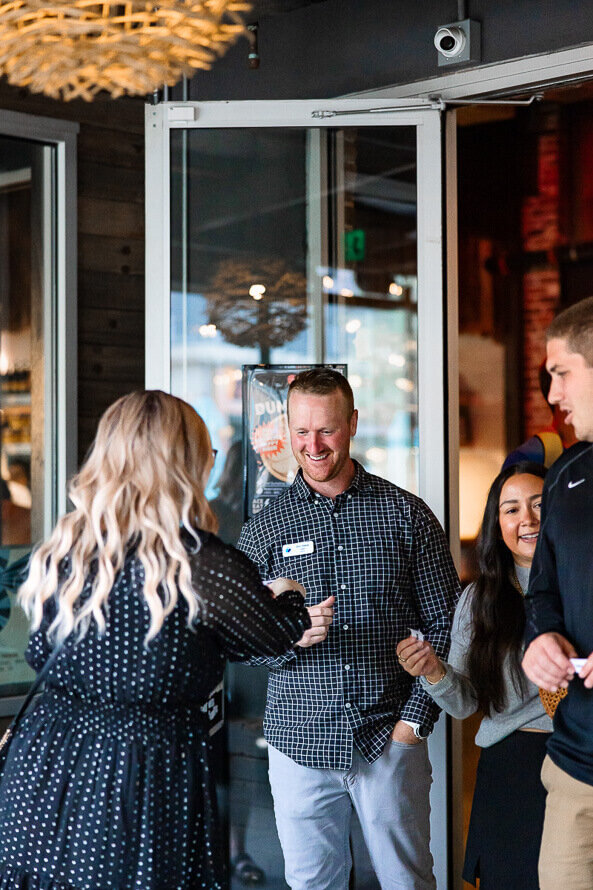 Man holds drink and laughs with co-workers at his works social event.