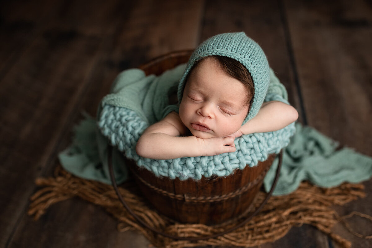 Baby boy in a wooden bucket during his baby photos session in New Ulm, Minnesota.