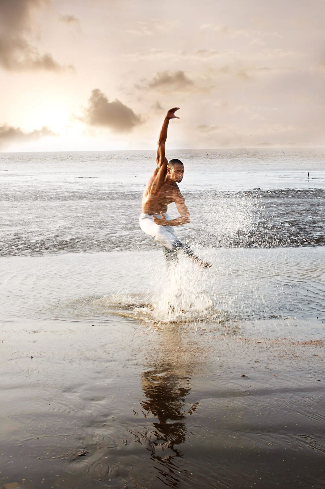 A person dancing at the water's edge as they kick water