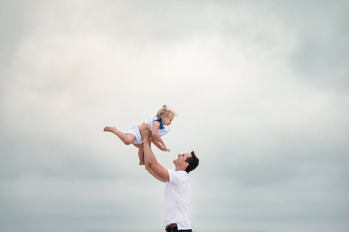 Father, tossing his toddler girl in the air on the beach in Stone, Harbor New Jersey