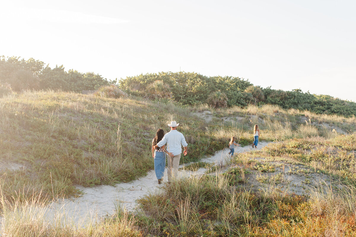 Family walking through the dunes during golden hour on the beach