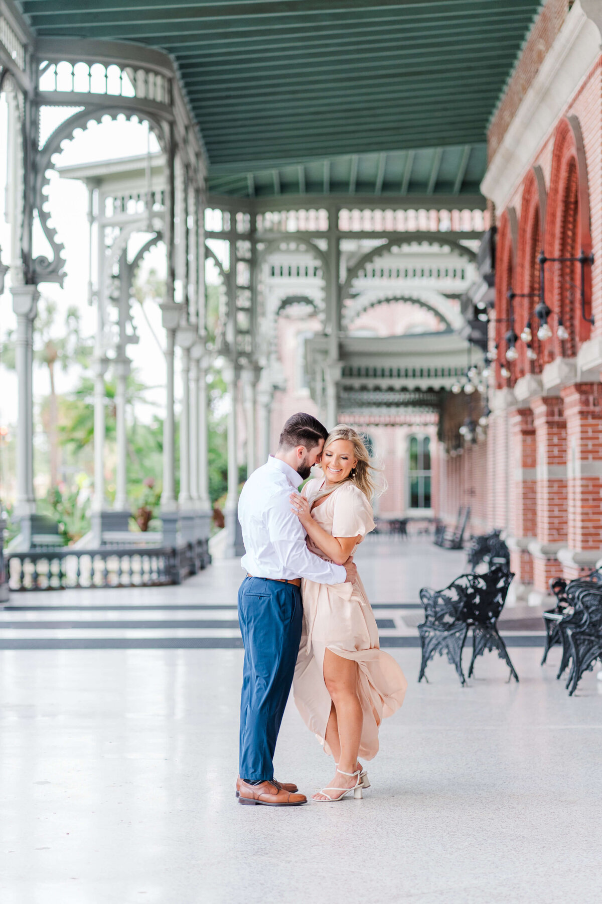 Couple embracing under Victorian-style architecture with ornate details in front of Henry B. Plant Museum.