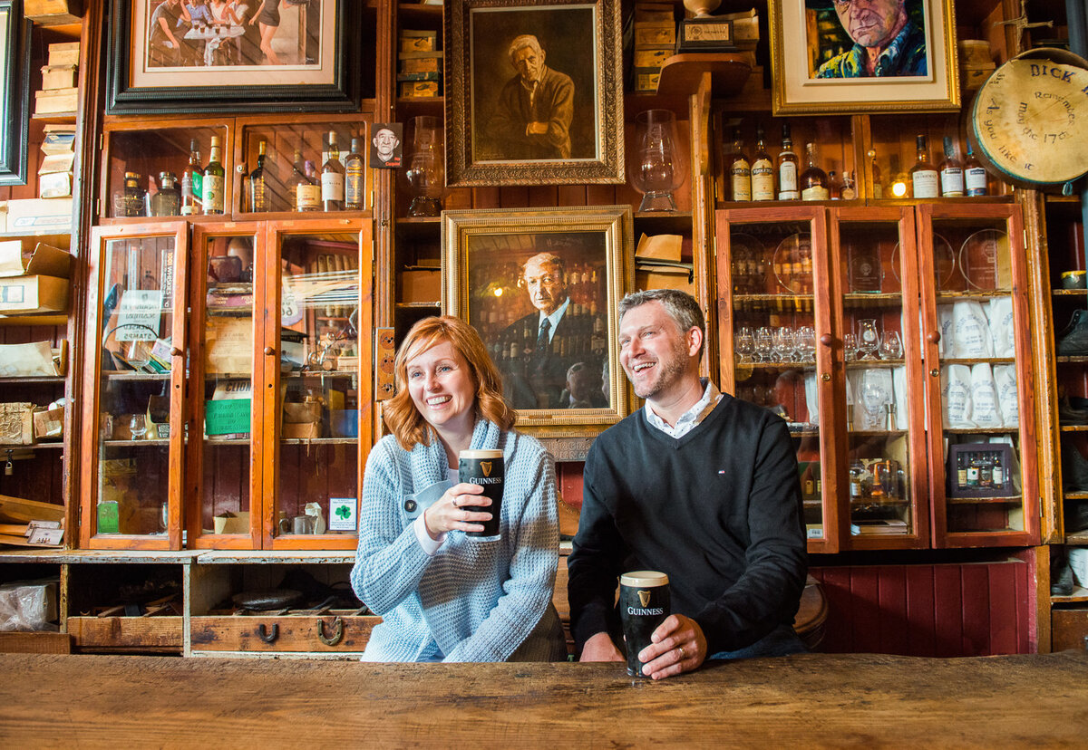 Couple sitting in an old pub in Dingle laughing and drinking Guinness