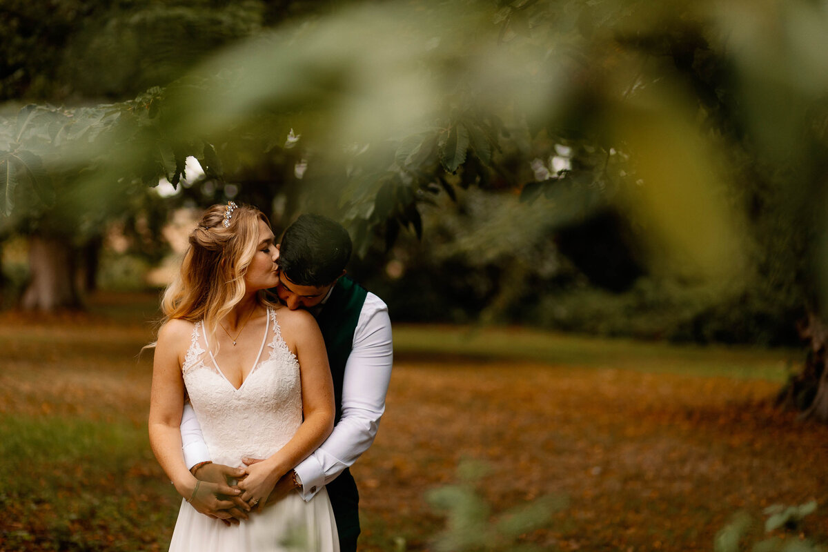 Bride and groom embracing in woodlands at Broughton Sanctuary