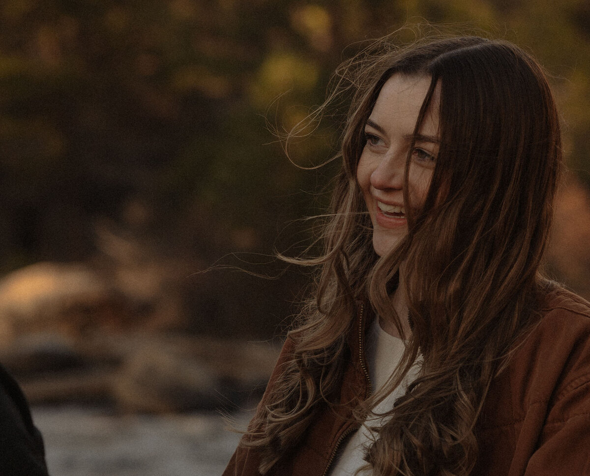 engaged woman smiles at her groom while the wind blows her hair in Bend, Oregon