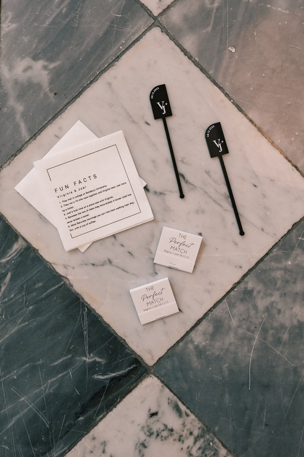 Elegant flatlay of wedding invitation suite, vow books, and YSL perfume bottle on marble floor at Hotel Monaco Washington DC.