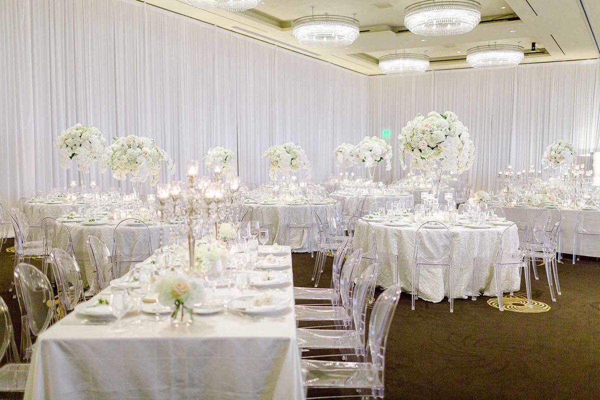 Four Seasons wedding reception Seattle in all white flowers, white linens, clear lucite chairs, with large white orchid centerpieces