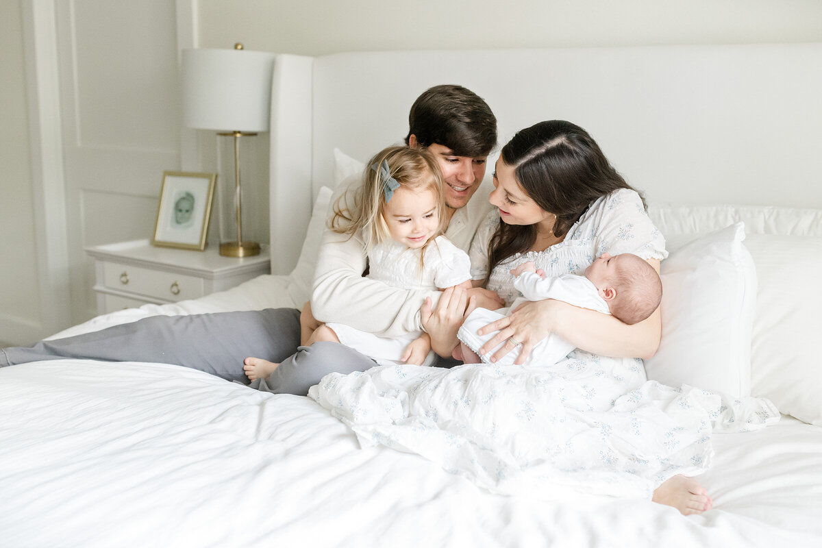 a family having fun with their newborn baby on a bed