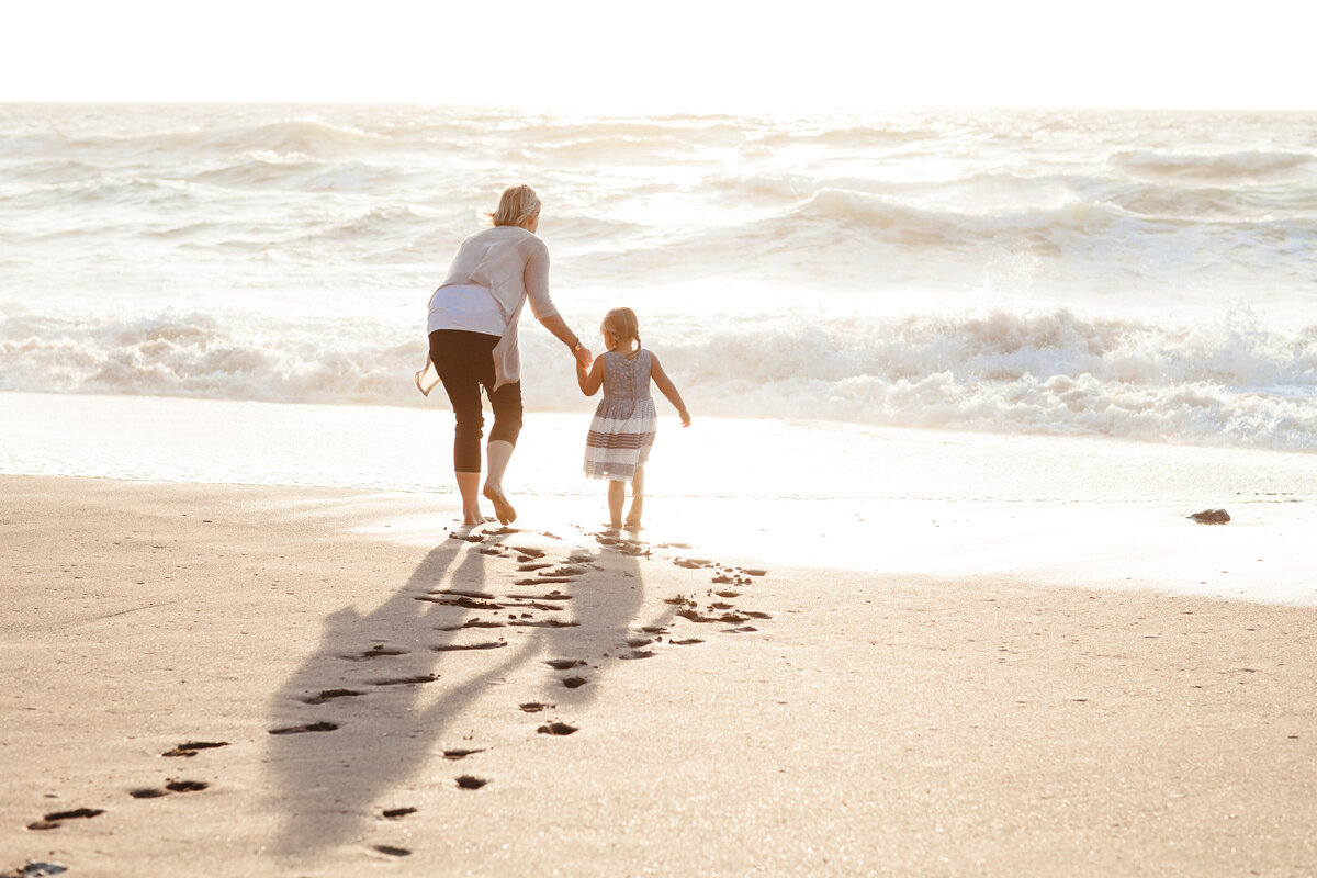 Mother and daughter paddle in the sea at sunset