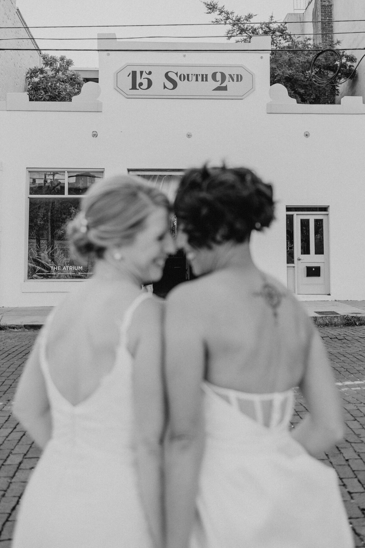 Two brides smiling happily at their atrium wedding in Wilmington, LGBTQ+ wedding photography