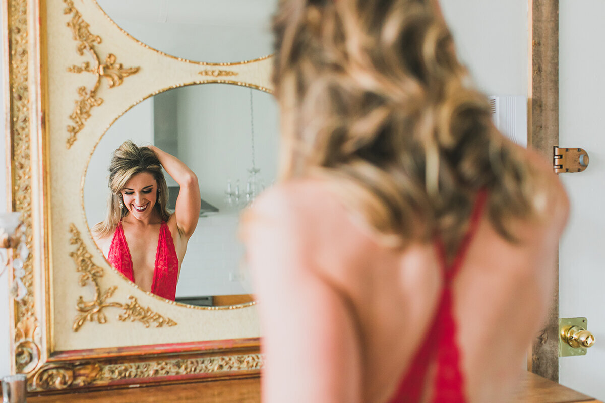 A mirror reflection boudoir photo of a woman wearing red lingerie