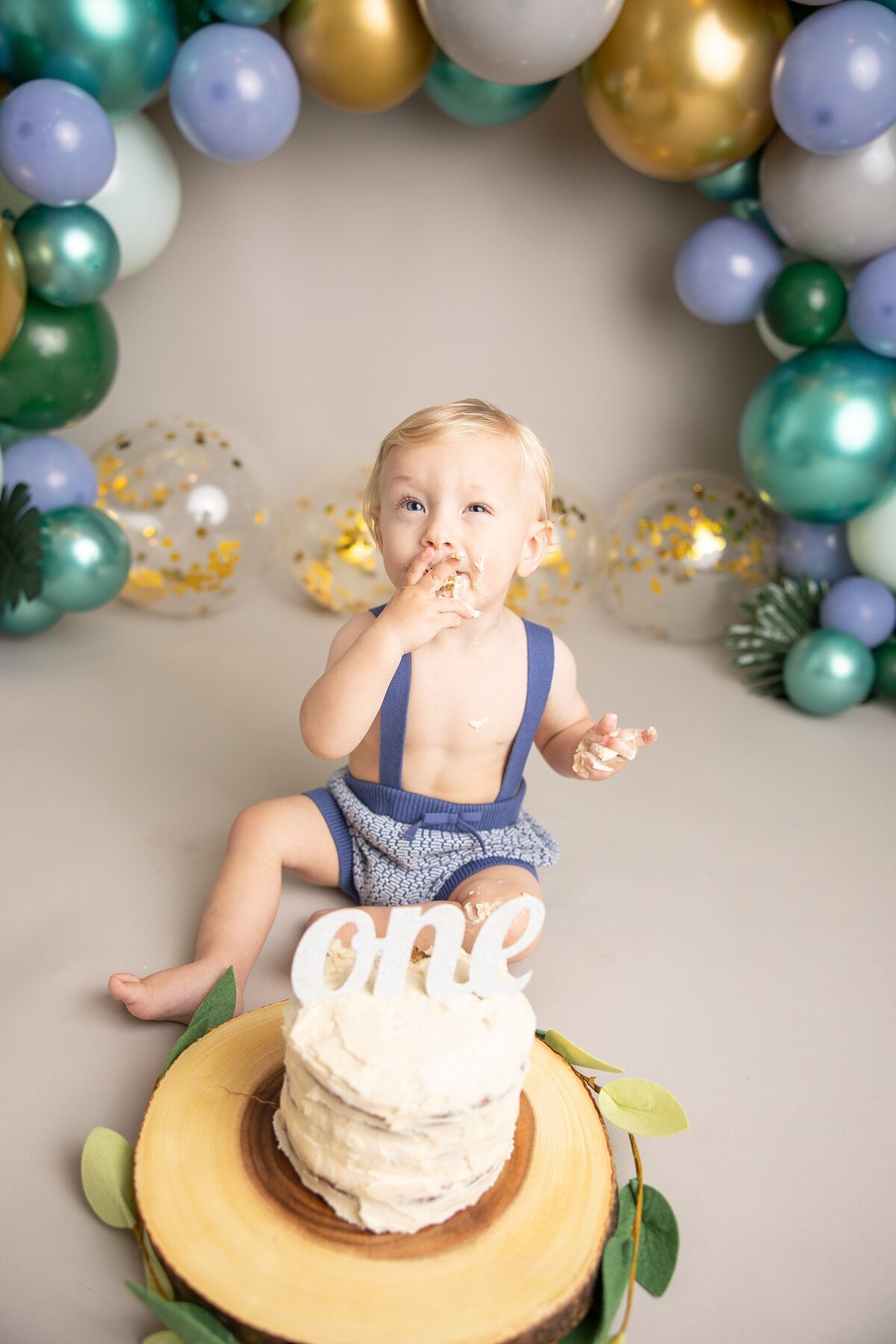 baby boy making silly face eating cake for first birthday session with Ann Marshall Photography cake smash near portland oregon