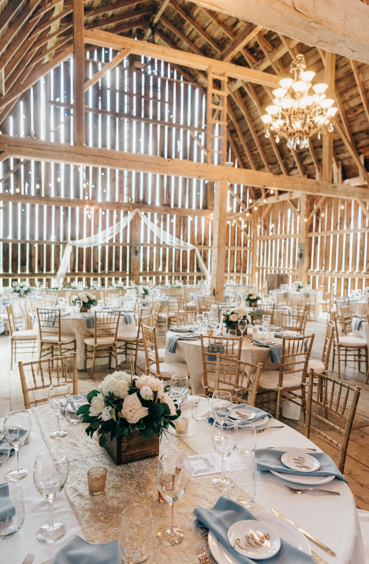 Gorgeous barn reception with white floral centre pieces, and white and blue themed decor
