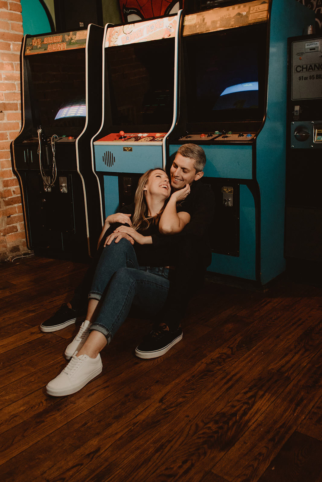A couple sitting down together against a vintage arcade game 