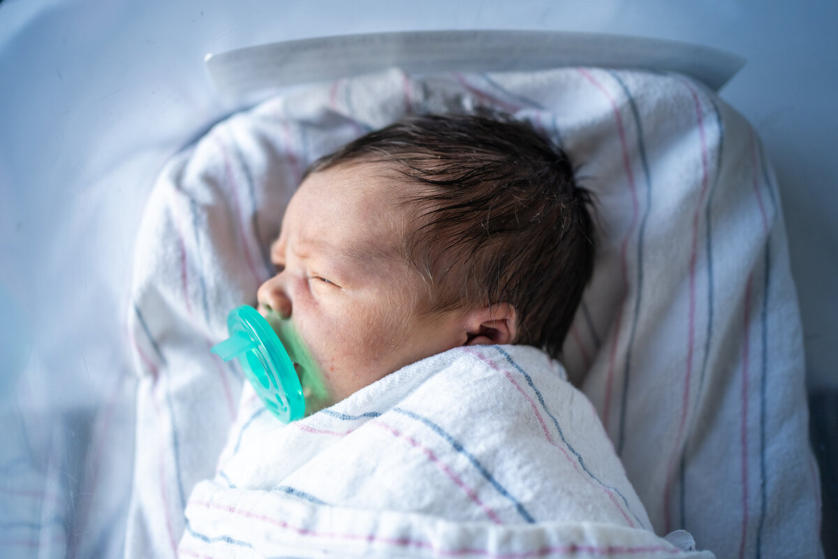 Sleeping newborn with pacifier in mouth