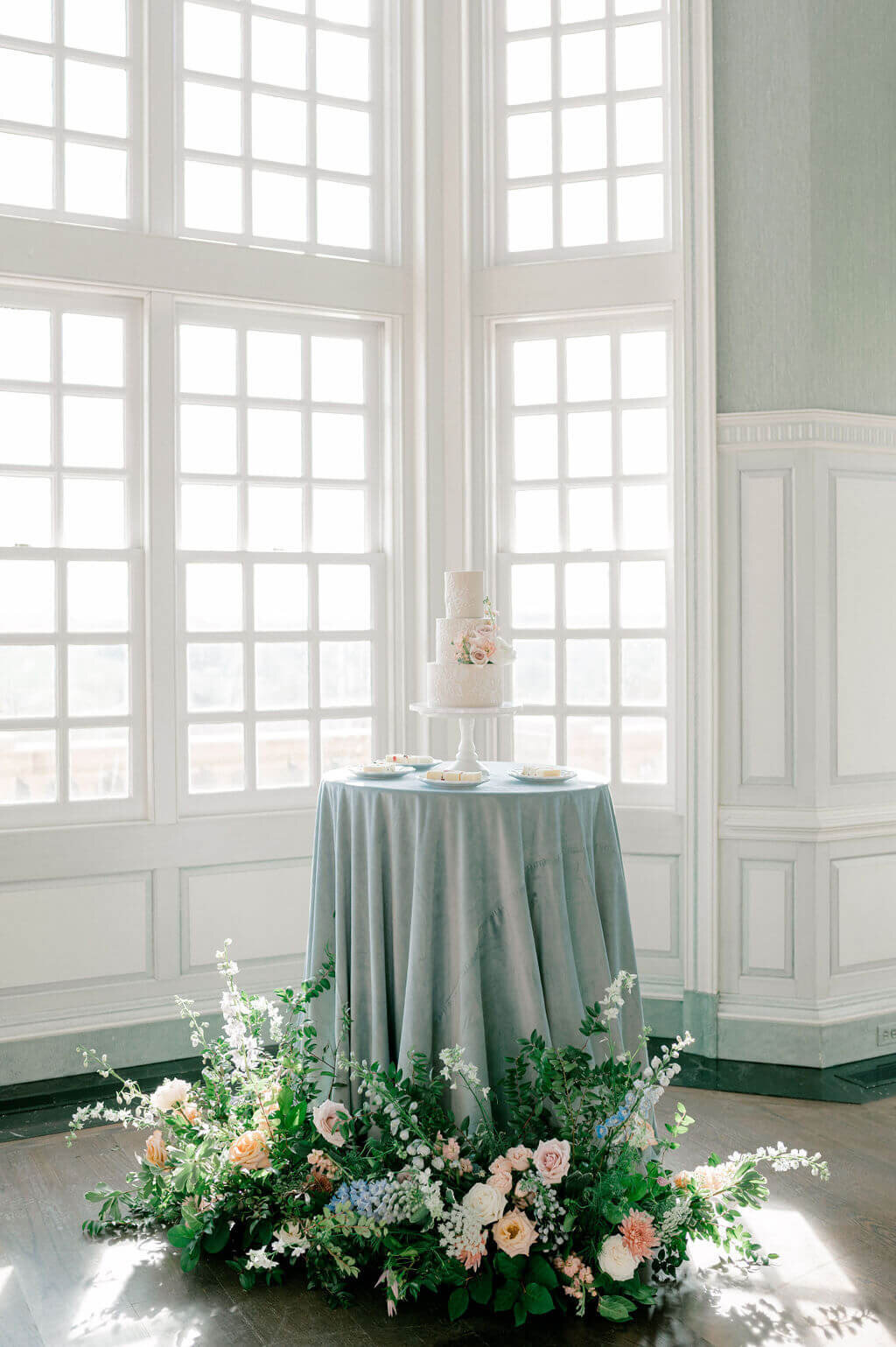 blue cake table surrounded by florals