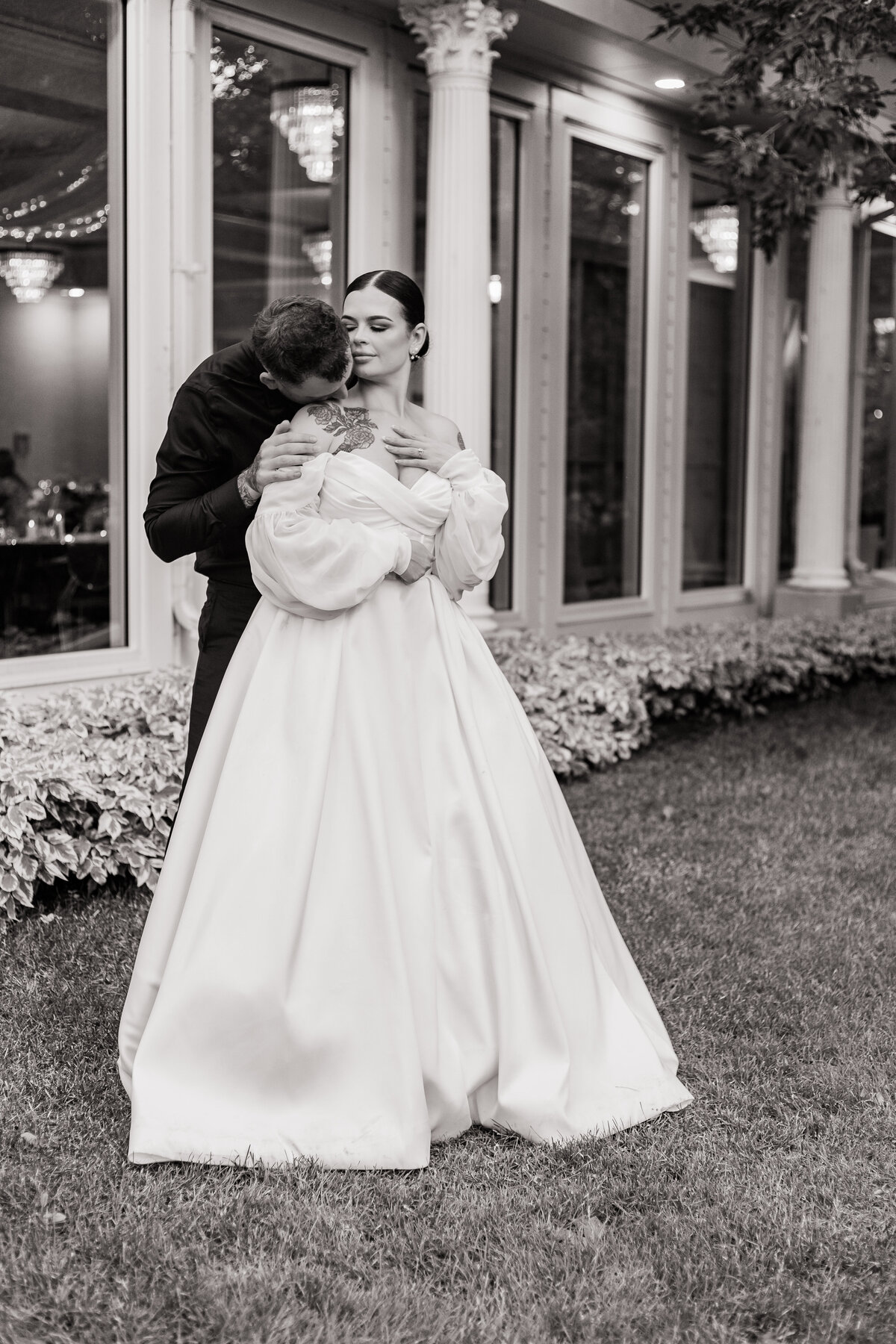 Groom kisses bride from behind outside their reception at the Norland Estate