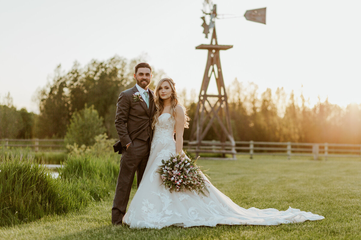 bride and groom posing by windmill