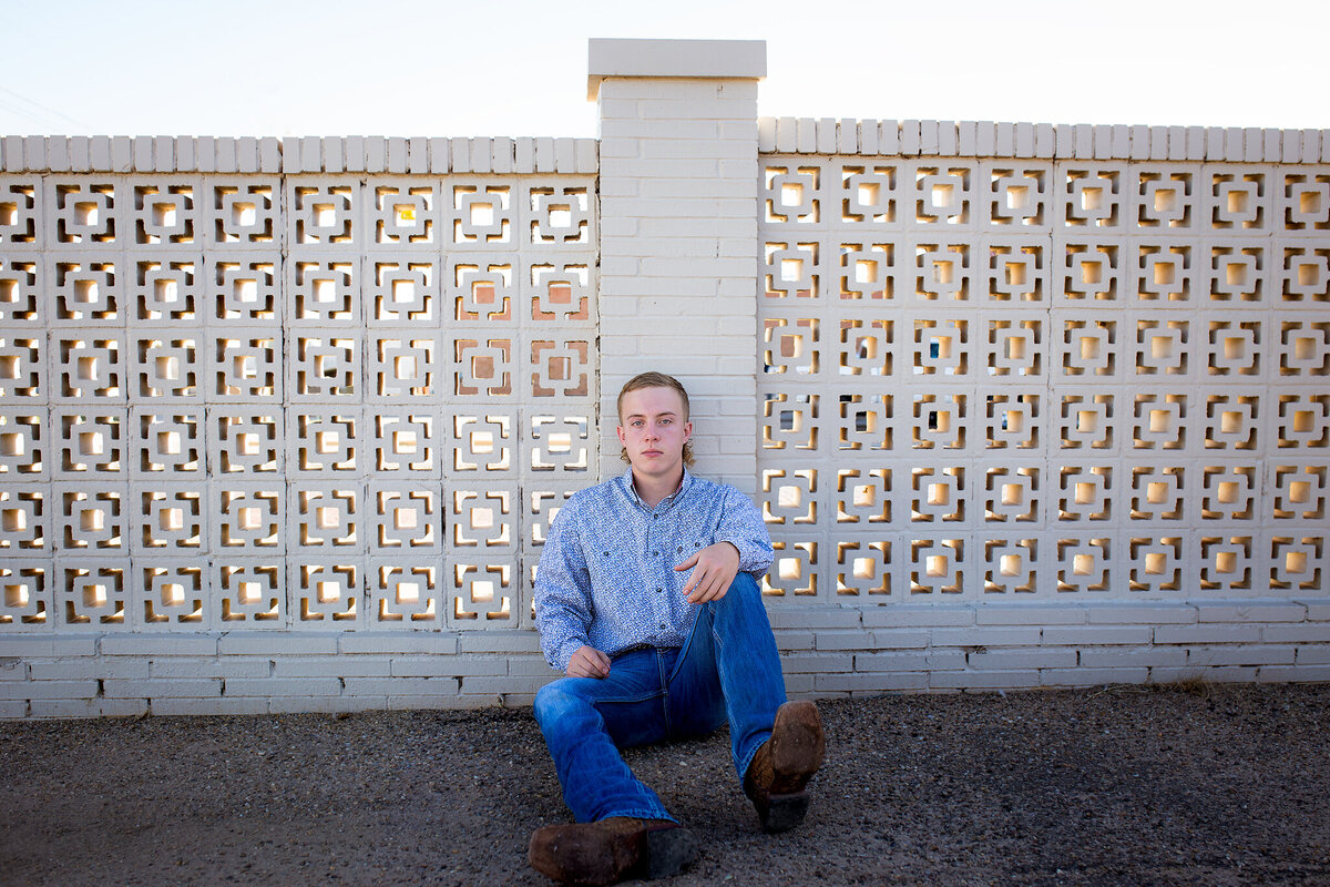 senior boy sitting against vintage concrete wall