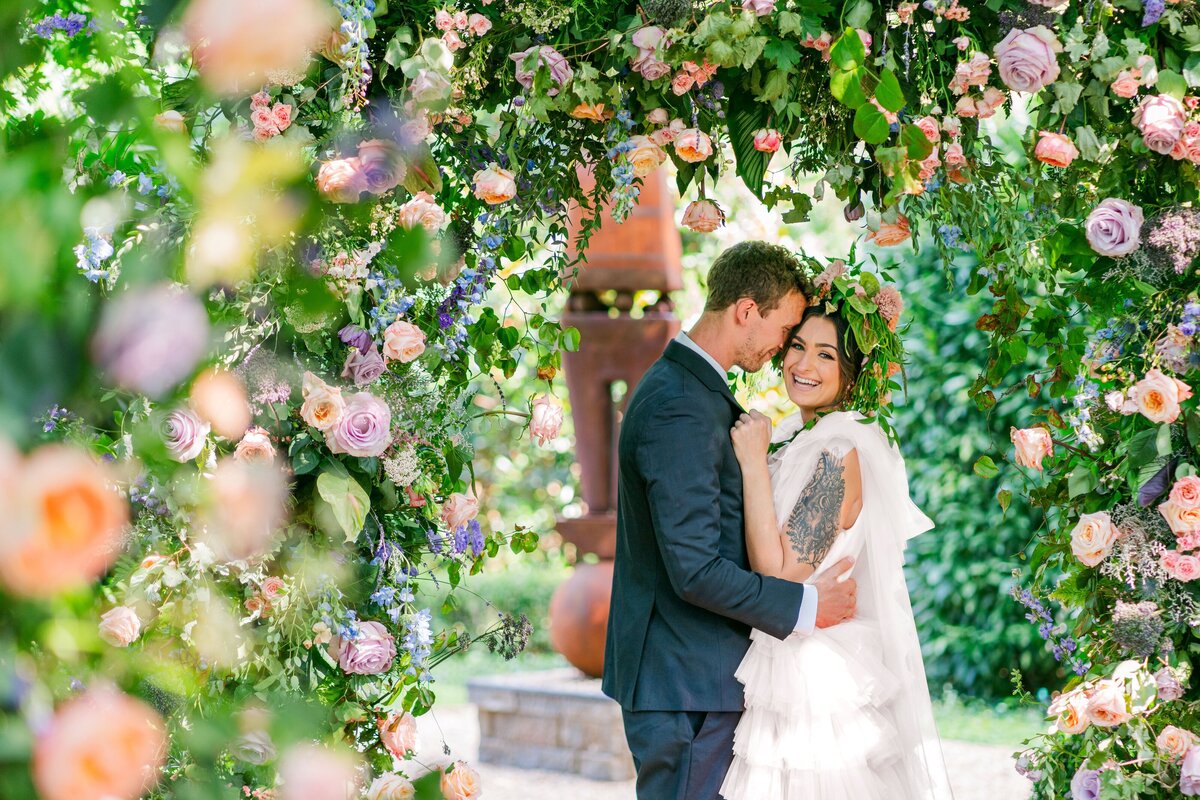 Couple embraces under floral archway on the wedding day in Charlotte