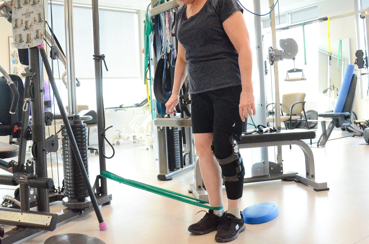 Woman standing and showing strength while wearing Summit Bracing and Orthotic Services knee brace, a medical device designed to provide support, stability, or alignment to the knee, foot, and ankle