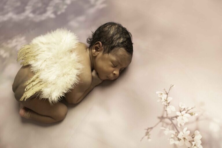 Newborn baby girl peacefully resting with delicate angel wings, creating a soft and ethereal portrait full of innocence and serenity