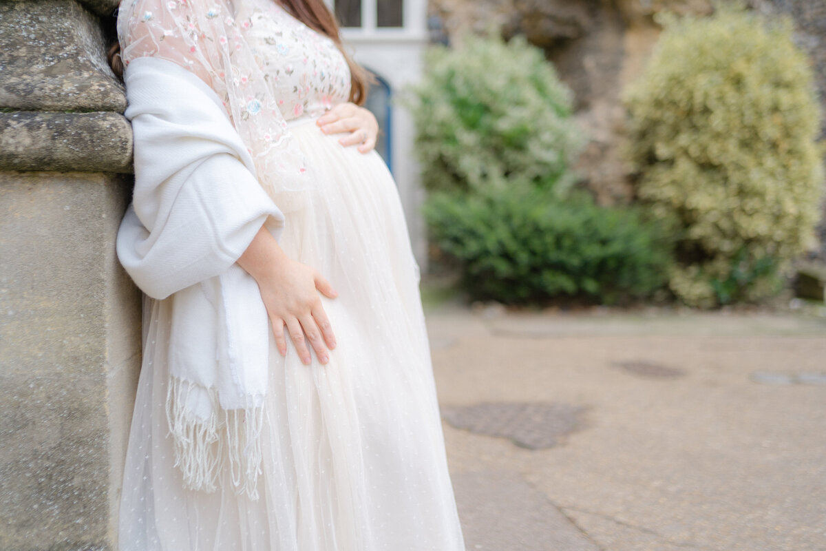 Detail shot of mother wearing a needle and thread gown with her hand on her bump by Maternity Photographer Courtney Cronin in Oklahoma City