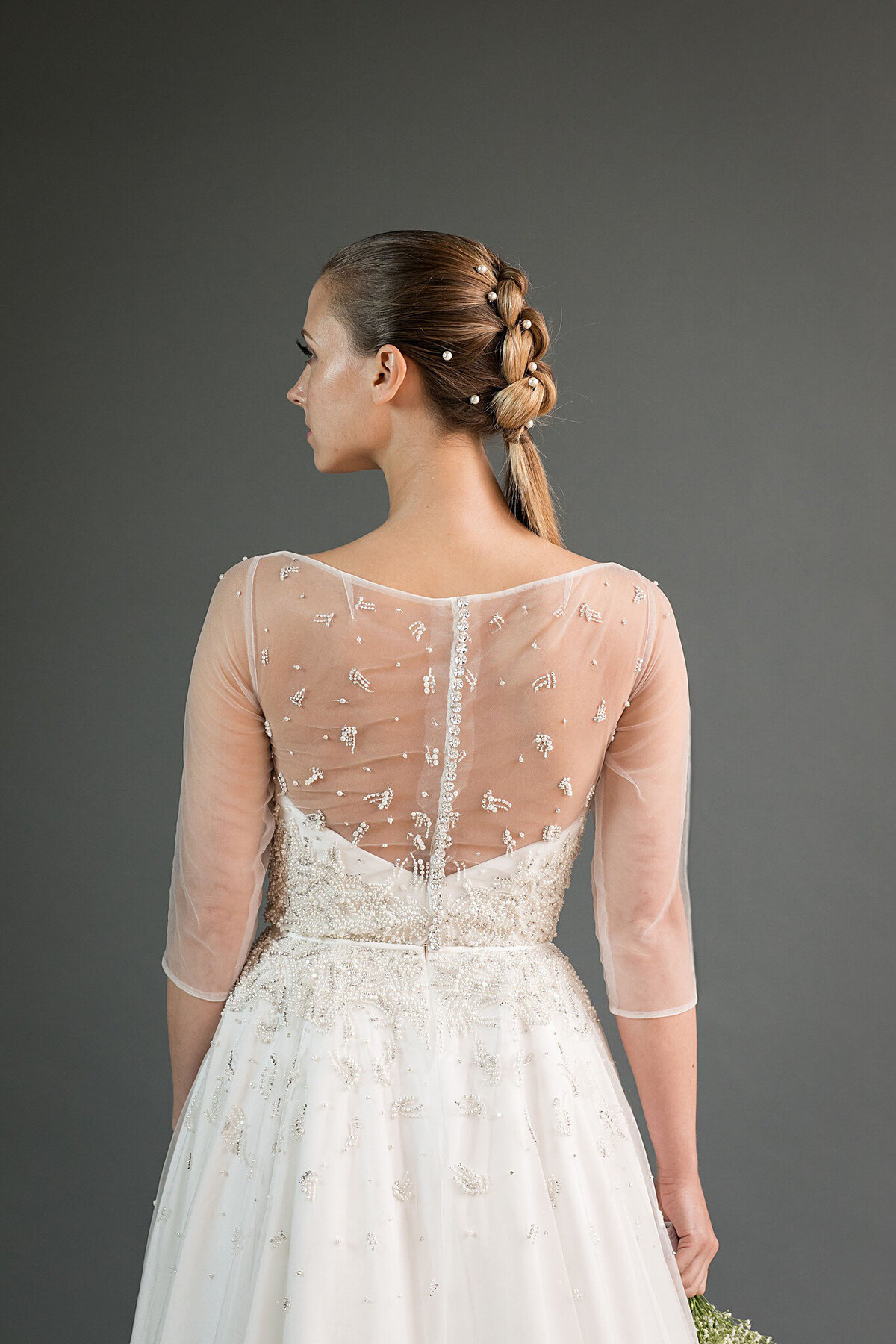 The strapless foundation of the Kei wedding dress style can be seen through the illusion back bodice. The illusion bodice itself features a crystal button closure down the back to the waistline.