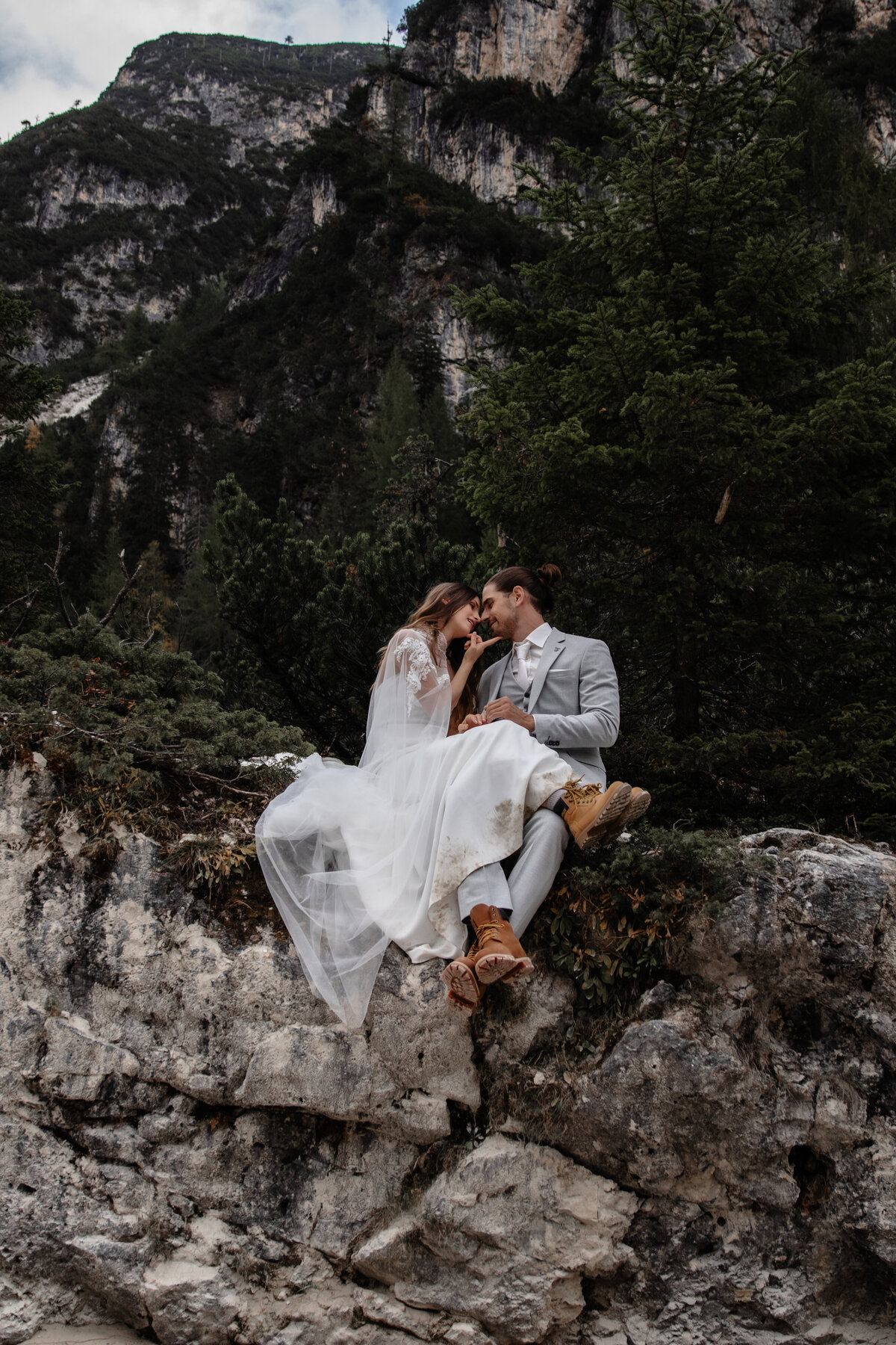 Elopement wedding couple posing on a cliffside with dramatic mountain views