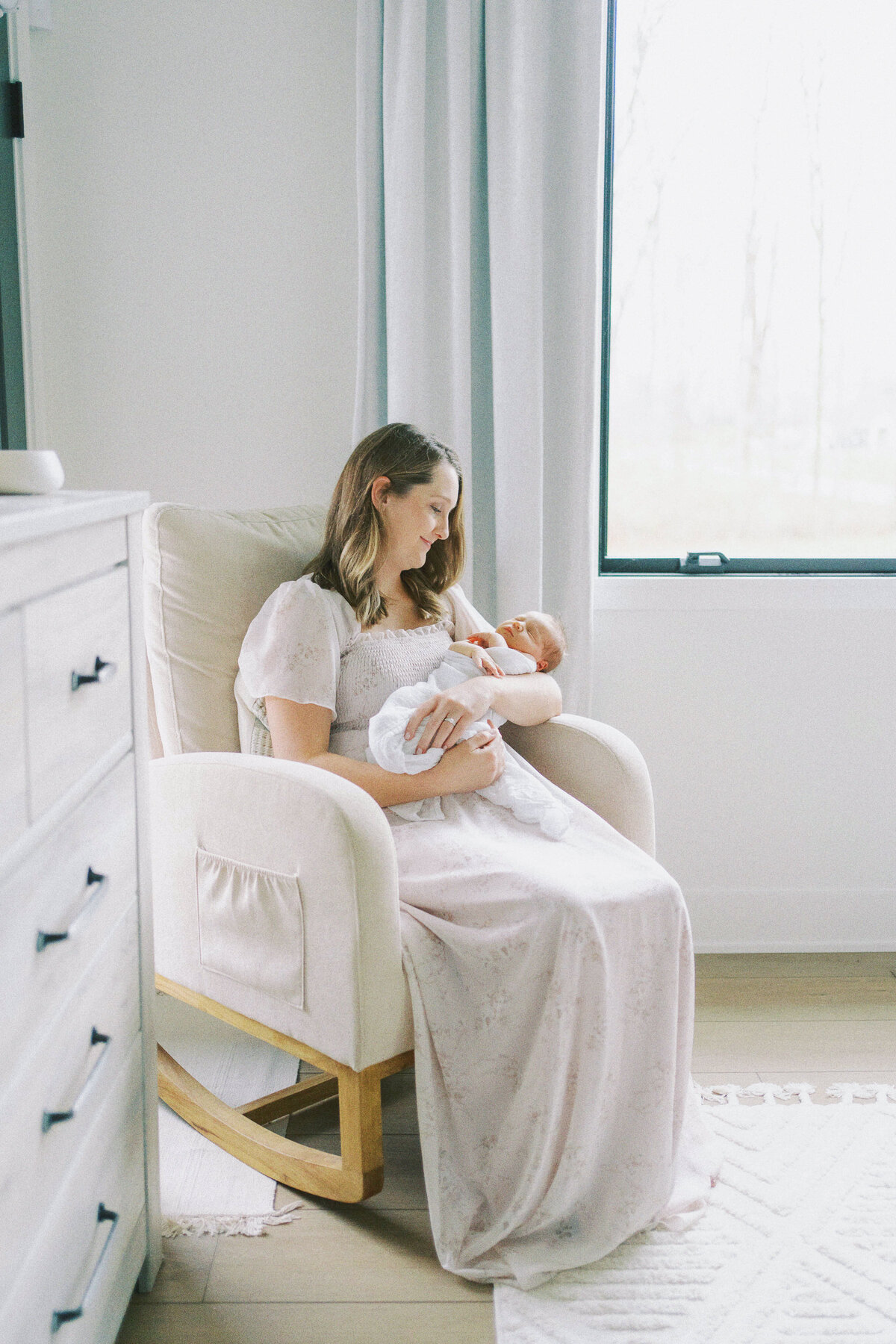 mom holding baby girl in nursery chair