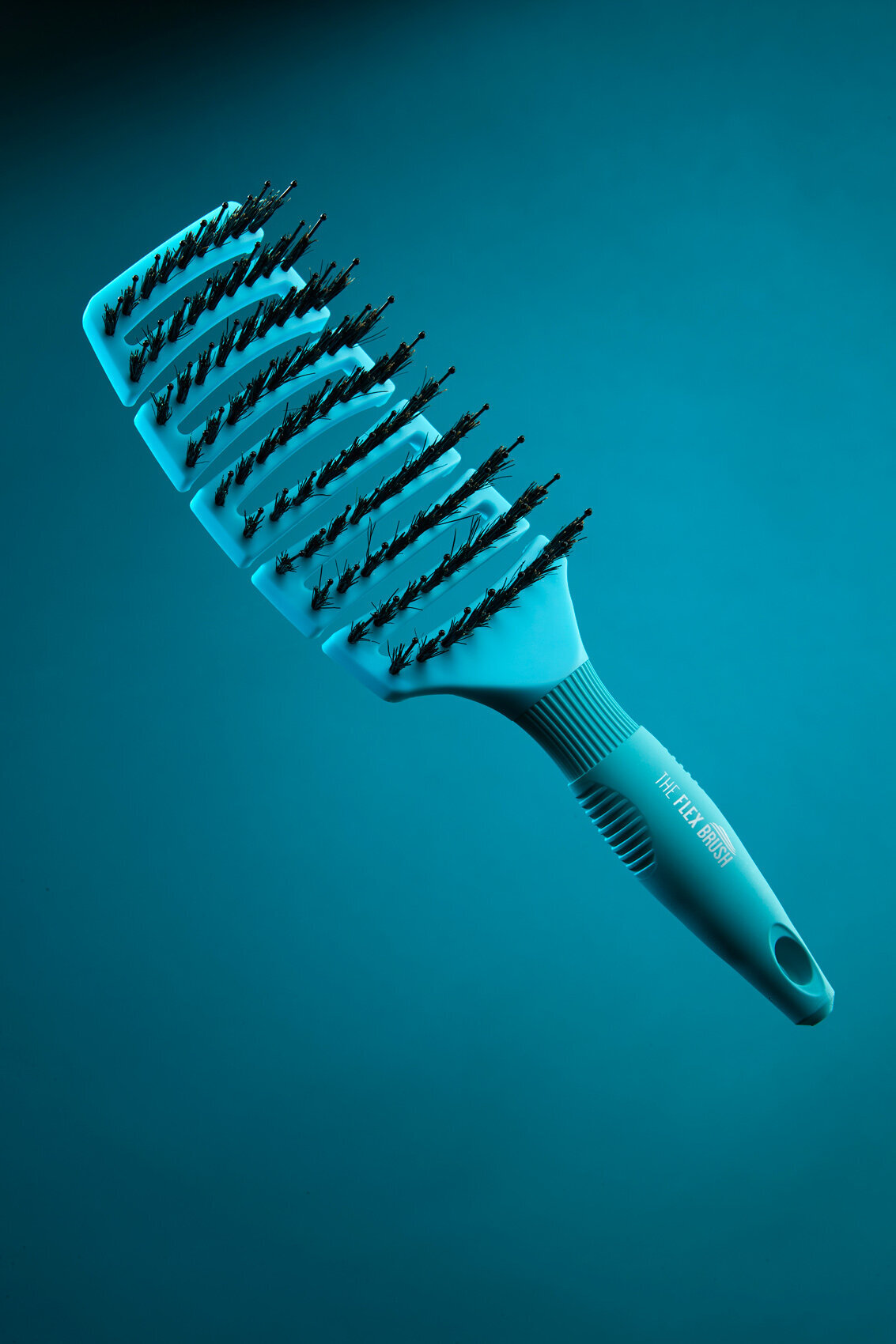 Close-up of The Flex Brush with a sleek design, displayed on a blue background, captured by Ylva Erevall.