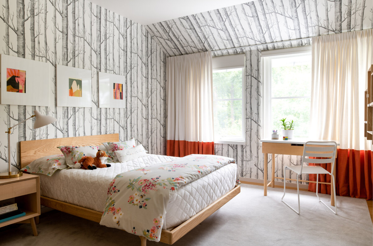 A young teen’s room in this Main Street Hingham home features Cole and Son black and white woodsy wallpaper, bold orange drapes, and handmade maple furniture. As seen in Boston Globe magazine.