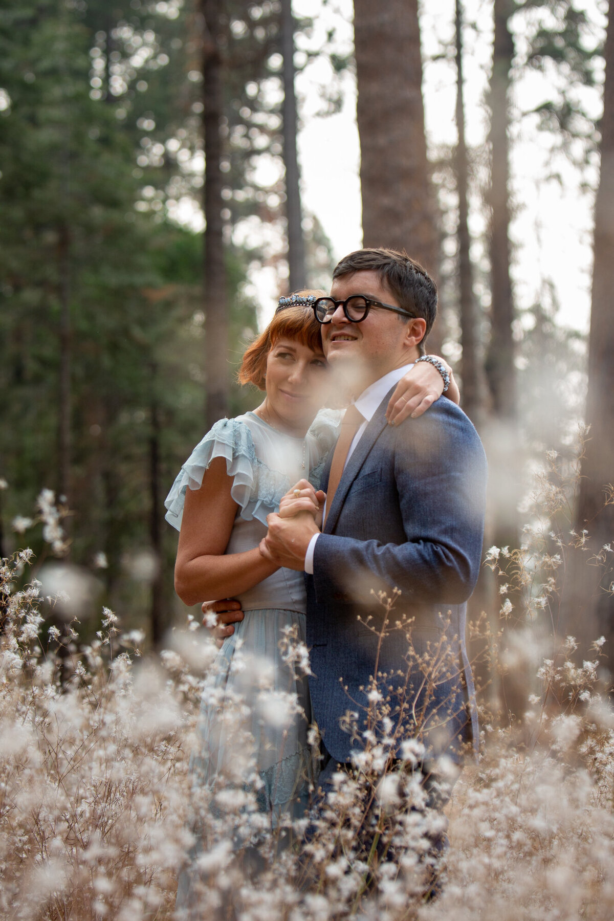 A bride and groom stand together in a field of flowers in Yosemite.