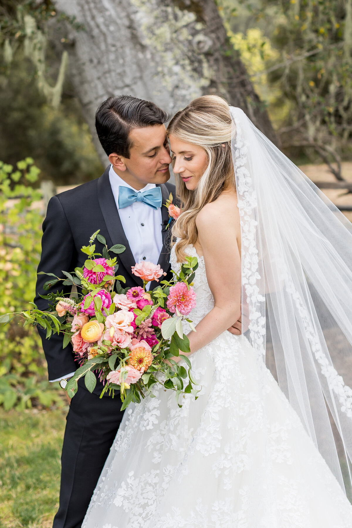 Groom in bowtie and bride holding flowers